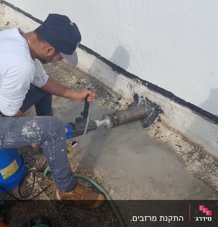 אדם קודח חור בגג עם מקדחה חשמלית